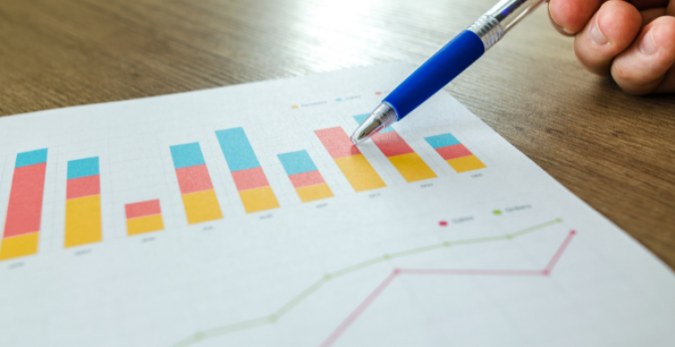 Bar charts with someone using a pen to point to the document