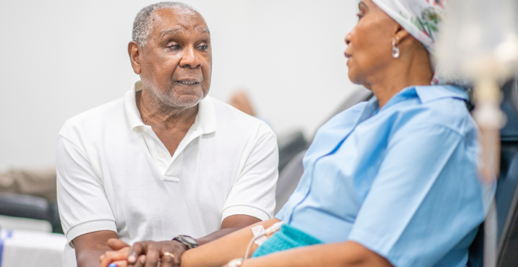 A woman in the oncology unit receiving chemotherapy treatment, accompanied by a man who is holding her hand.