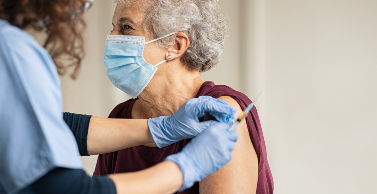 An older woman wearing a face mask receiving a vaccine