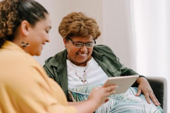 Two people sitting on a sofa looking at a tablet